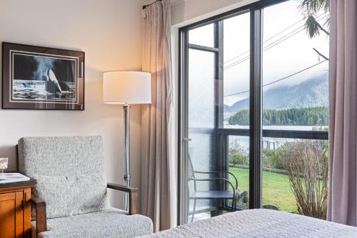 a bedroom with a bed and a chair and a window at Tofino Motel Harbourview in Tofino