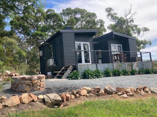 una casetta nera sul ciglio di una strada di Hayshed Cabins - Merigan Farm Stay a Tarago