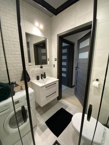 a bathroom with a sink and a toilet and a mirror at ST TOWER Apartament in Rzeszów