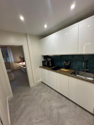 a kitchen with white cabinets and a sink at Studio Villennes sur seine cosy Paris Versailles in Villennes-sur-Seine