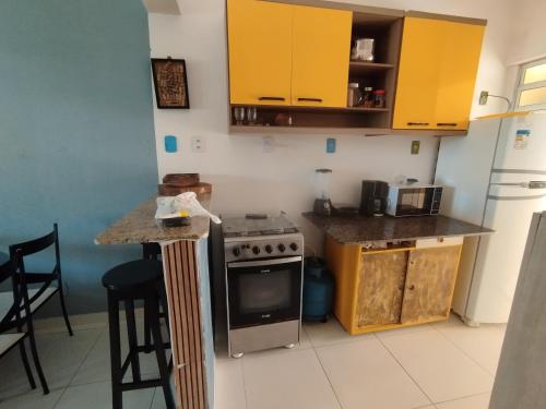 a kitchen with yellow cabinets and a stove at Recanto Casa SOL in Barra de Jacuípe
