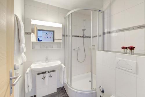 a white bathroom with a shower and a sink at Good Value Apartments by Mountain Exposure in Zermatt