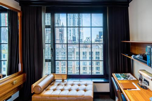 a room with a couch in front of a large window at Le Meridien New York, Central Park by Marriott in New York