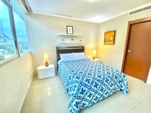 a bedroom with a bed with a blue and white bedspread at Departamento con Piscina en el último piso del edificio in Guayaquil