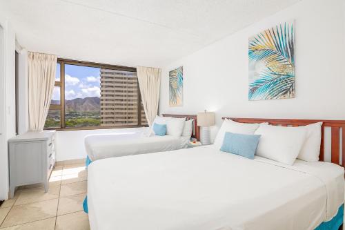 two beds in a room with a window at Waikiki Banyan 15FL - views, pool & hot tub access in Honolulu