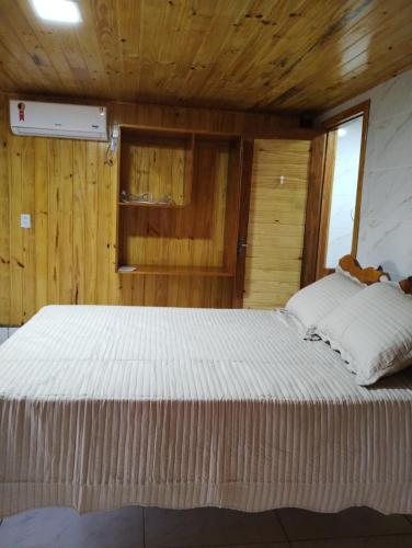 Cama grande en habitación con techo de madera en Hotel Fazenda Rancho Grande, en Linha Blinda