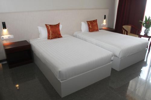 two beds in a hotel room with white sheets and red pillows at Flow Hotel Benguela in Benguela