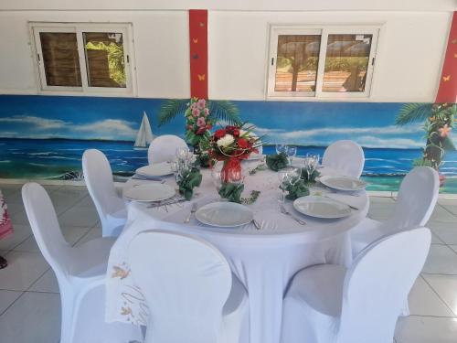 a white table with white chairs and flowers on it at Les Villas de Boisvin in Le Moule