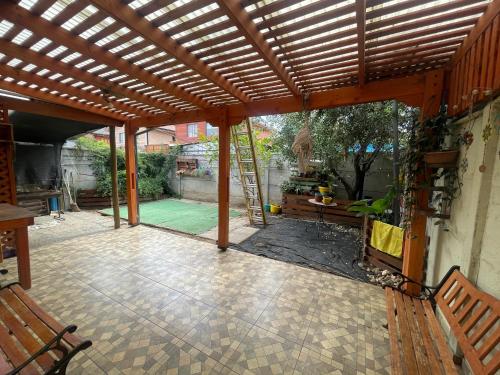 an outdoor patio with a wooden pergola with benches at Casa Talca in Talca