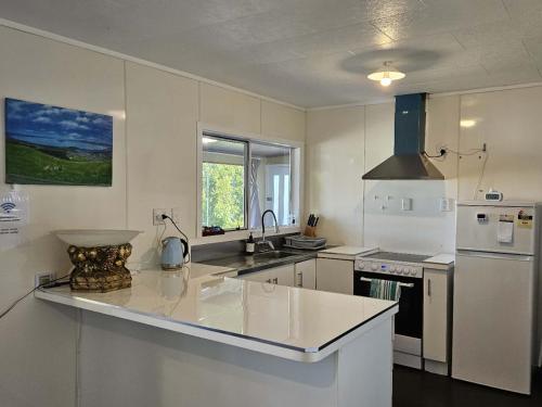a white kitchen with a sink and a refrigerator at Aorangi Peak Cottage in Rotorua