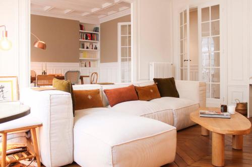 een woonkamer met een witte bank en een tafel bij Spacious haussmann apartment in Parijs