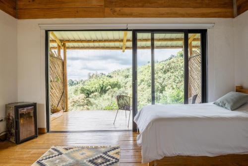 een slaapkamer met een bed en een groot glazen raam bij El Fenix Coffee in Calarcá