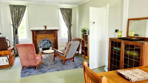 a living room with a fireplace and a table and chairs at Truffle Honey Cottage in Warkworth