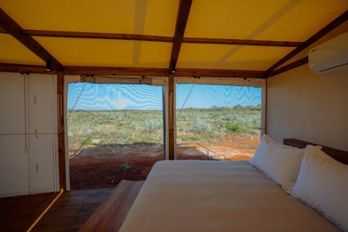 a bedroom with a bed with a view of a field at Viatura Hacienda Xtojil, Yucatan, Merida, with Optional All Inclusive in Sotuta de Peón