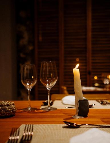 a candle sitting on a table with two wine glasses at Viatura Hacienda Xtojil, Yucatan, Merida, with Optional All Inclusive in Sotuta de Peón
