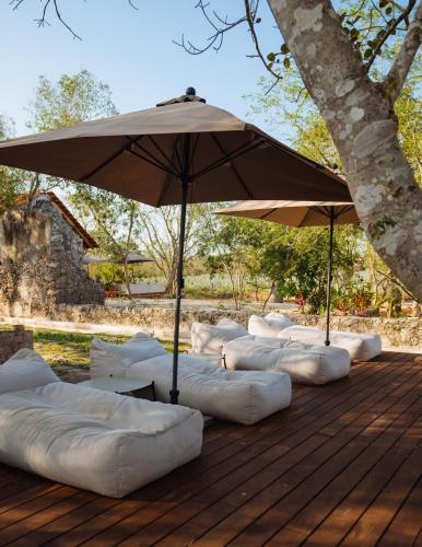 a row of sleeping bags under an umbrella on a deck at Viatura Hacienda Xtojil, Yucatan, Merida, with Optional All Inclusive in Sotuta de Peón