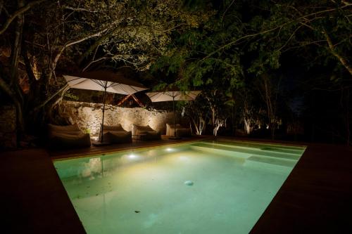 a swimming pool at night with an umbrella at Viatura Hacienda Xtojil, Yucatan, Merida, with Optional All Inclusive in Sotuta de Peón