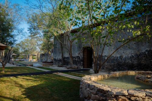 an old stone building with a hot tub in a yard at Viatura Hacienda Xtojil, Yucatan, Merida, with Optional All Inclusive in Sotuta de Peón