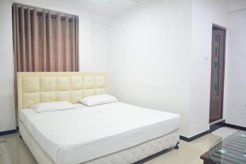 1 dormitorio con 1 cama blanca y ventana en Saasha City Hotel, en Colombo