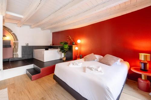 une chambre avec un lit blanc et un mur rouge dans l'établissement LE MACARON - Cozy flat in the heart of the old town, à Annecy