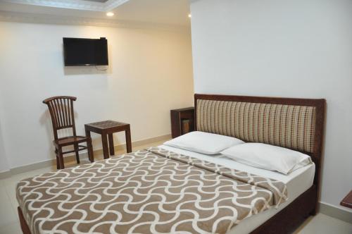 a bedroom with a bed and a tv on the wall at Saasha City Hotel in Colombo