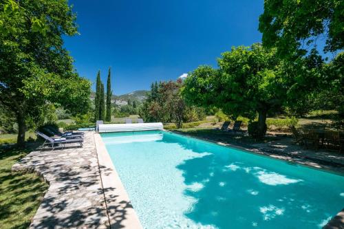 a swimming pool in a yard with chairs and trees at Villa Les Saffres in Malaucene in Malaucène