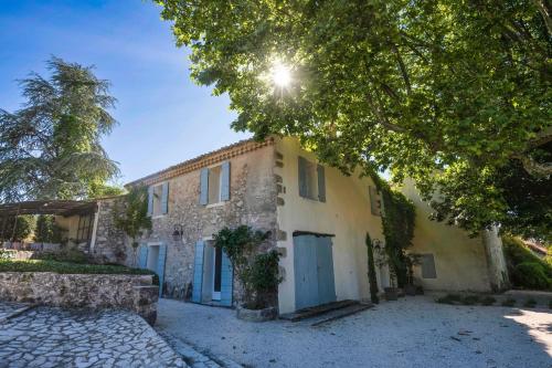 une vieille maison en pierre avec des portes bleues dans une rue dans l'établissement Villa Les Saffres in Malaucene, à Malaucène