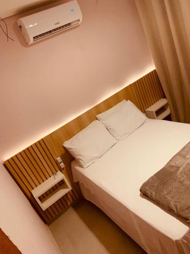a small bedroom with a bed and a air conditioner at Sol de Corumbau in Corumbau
