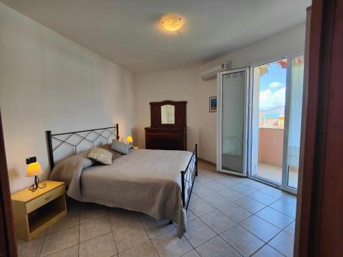 a bedroom with a bed and a sliding glass door at SMERALDA in Alghero