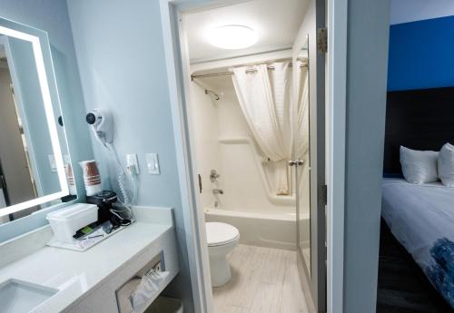 a bathroom with a toilet and a sink and a tub at Baymont by Wyndham Branson Thousand Hills in Branson