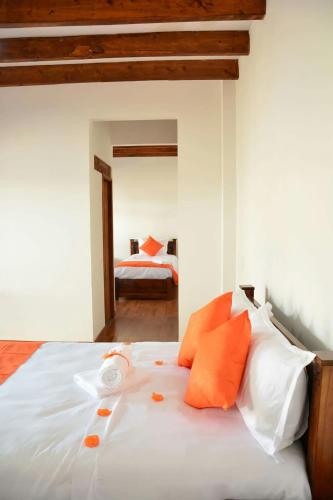 a bedroom with a bed with orange and white pillows at Hotel Gran Sirius in Sáchica