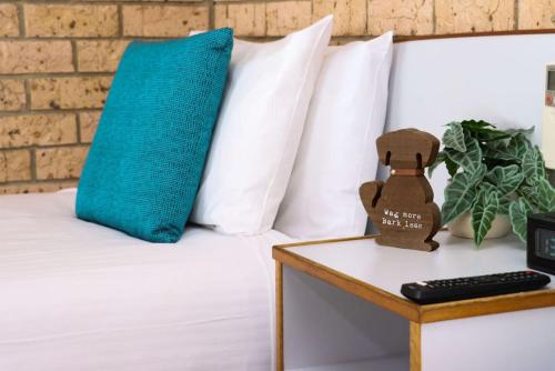a bed with a blue pillow on a table at Kennedy Drive Boutique Motel - Close To City Centre & Airport in Tweed Heads