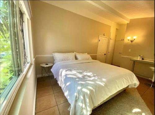 um quarto com uma cama branca e uma janela em West Beach Treehouse em Santa Bárbara
