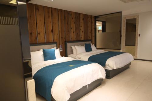 2 łóżka w sypialni z drewnianymi ścianami w obiekcie JB Tourist Hotel w mieście Daegu