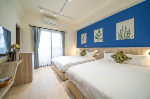 1 dormitorio con 2 camas y pared azul en 田園走走 en Jiaoxi