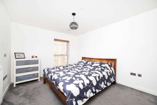 a bedroom with a bed with a black and white comforter at Stylish 1BR Flat with Balcony Near Tube and Shops in Woolwich