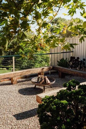 a wooden bench and a table in a garden at Sand Road Estate in McLaren Flat