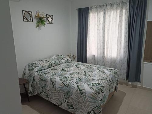 Un dormitorio con una cama y una ventana grande. en Departamento Planta Baja, A 1 Minuto de la playa., en Mazatlán