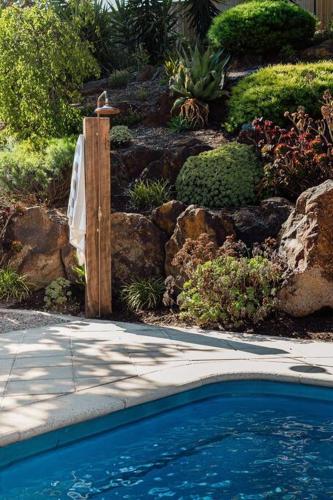 a swimming pool in a garden with a fence and rocks at Sand Road Estate in McLaren Flat