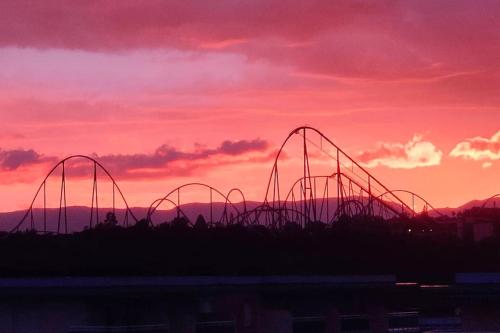 a roller coaster in front of a sunset at Pineda apartamento de playa in La Pineda
