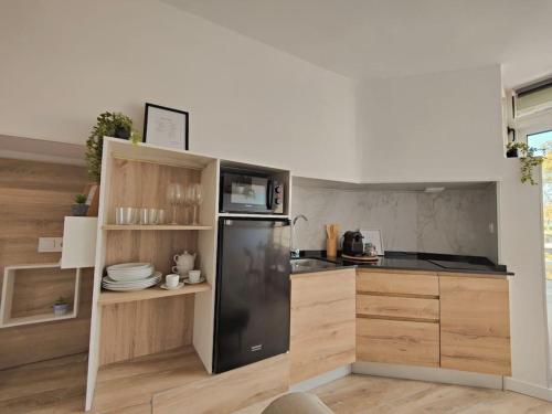 a kitchen with a black refrigerator and wooden cabinets at Pineda apartamento de playa in La Pineda