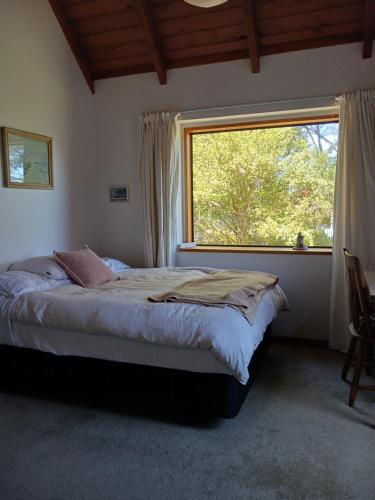 a bedroom with a bed and a large window at The Annex in Whitianga