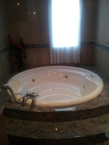 a large tub in a bathroom with a window at Hotel Flor de la Mancha in La Roda