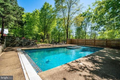 una piscina en un patio con una valla en Tara Retreat: Family-Friendly Oasis with Pool, Tennis & Serene Ambiance in Potomac, en Potomac