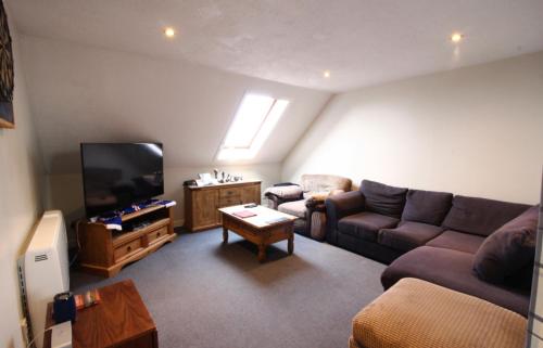 a living room with a couch and a flat screen tv at Orkney lux apartment in Orkney