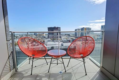 two red chairs and a table on a balcony at Enchanting at Rowlands Central Mkt Cityview Wifi in Adelaide