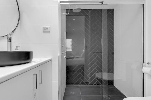 une salle de bain avec une douche avec un lavabo et un miroir dans l'établissement 2BR Townhouse CBD Chinatown Free WiFi FreeParking, à Adélaïde
