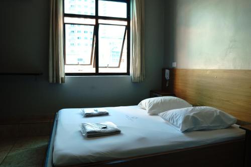 a bed with two towels on it with a window at Hotel city Clélia in Sao Paulo