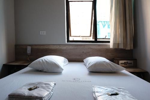 a bedroom with a bed with two pillows and a window at Hotel city Clélia in Sao Paulo