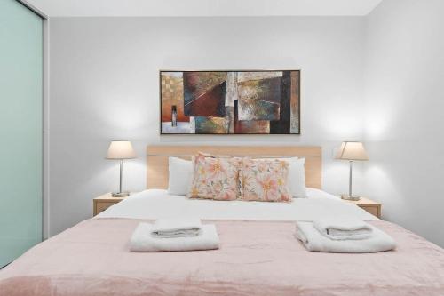 een slaapkamer met een groot wit bed met 2 lampen bij The CBD Hidden Gem 1BR Central & Walkable Haven in Adelaide
